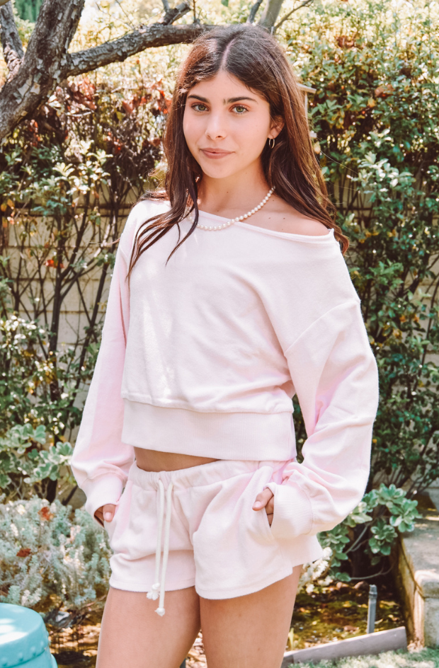 Girl wearing a pink off-shoulder top and shorts set in an outdoor setting.