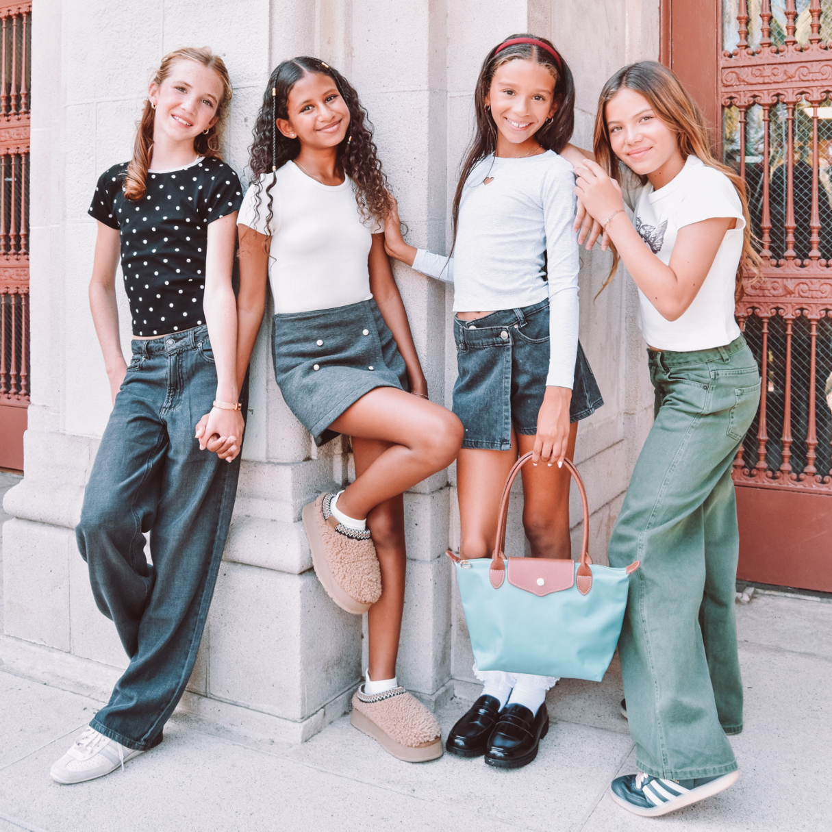 Four girls standing together in an array of cool-girl denim outside of school.